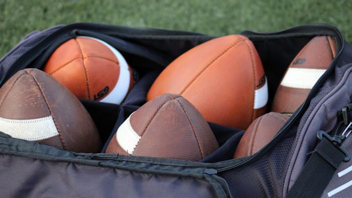 Footballs rest in a bag at a high school football game