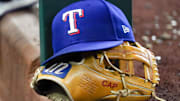 A Texas Rangers cap and baseball mitt sit on the dugout steps during a game against the Athletics at Globe Life Field. 