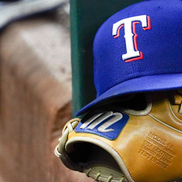 A Texas Rangers cap and baseball mitt sit on the dugout steps during a game against the Athletics at Globe Life Field.