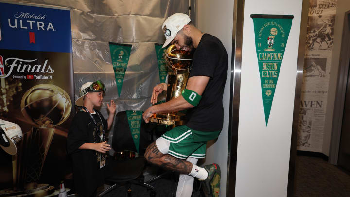 Boston Celtics star Jayson Tatum holds the Larry O’Brien Championship Trophy with his son after Game 5 of the 2024 NBA Finals at TD Garden.