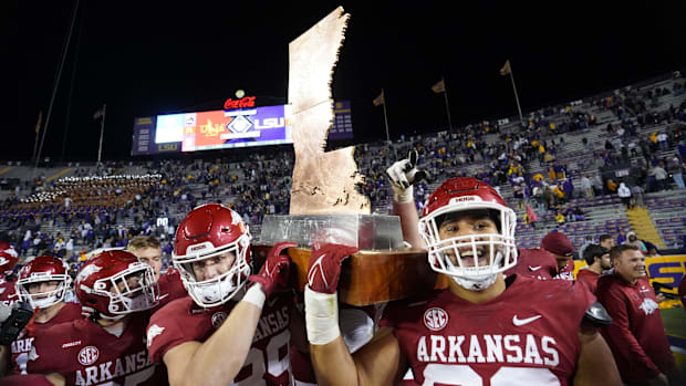 Arkansas Razorbacks players celebrate with the Boot trophy after defeating the LSU Tigers at Tiger Stadium