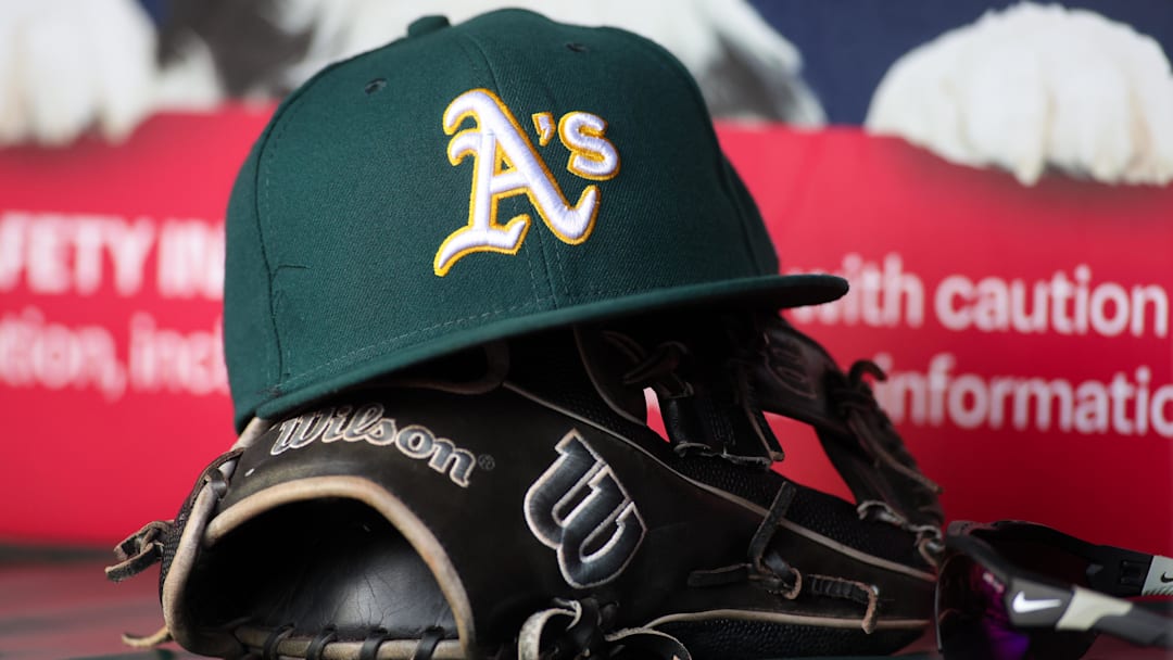 Jun 1, 2024; Atlanta, Georgia, USA; A detailed view of an Oakland Athletics hat and glove on the field against the Atlanta Braves in the sixth inning at Truist Park. Mandatory Credit: Brett Davis-Imagn Images Jun 1, 2024; Atlanta, Georgia, USA; A detailed view of an Oakland Athletics hat and glove on the field against the Atlanta Braves in the sixth inning at Truist Park. Mandatory Credit: Brett Davis-Imagn Images