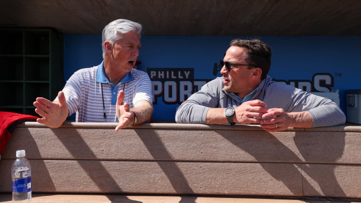 Feb 25, 2024; Clearwater, Florida, USA;  Philadelphia Phillies president of baseball operations Dave Dombrowski and general manager Sam Fuld talk in the dugout before a game against the New York Yankees at BayCare Ballpark. 