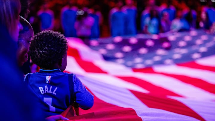 Apr 7, 2024; Charlotte, North Carolina, USA; Young fan holds American flag before the game between the Charlotte Hornets and the Oklahoma City Thunder at Spectrum Center. Mandatory Credit: Scott Kinser-Imagn Images