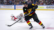 Oct 28, 2024; Vancouver, British Columbia, CAN; Vancouver Canucks forward Daniel Sprong (91) and Carolina Hurricanes goalie Pyotr Kochetkov (52) look at the flying puck after Kocketkov dove to poke check Sprong during the third period at Rogers Arena. Mandatory Credit: Bob Frid-Imagn Images