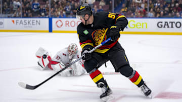 Oct 28, 2024; Vancouver, British Columbia, CAN; Vancouver Canucks forward Daniel Sprong (91) and Carolina Hurricanes goalie Pyotr Kochetkov (52) look at the flying puck after Kocketkov dove to poke check Sprong during the third period at Rogers Arena. Mandatory Credit: Bob Frid-Imagn Images