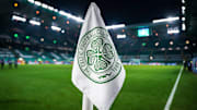 Detailed shot of a corner flag with the Celtic Glasgow coat of arms, illuminated stadium in the background. 