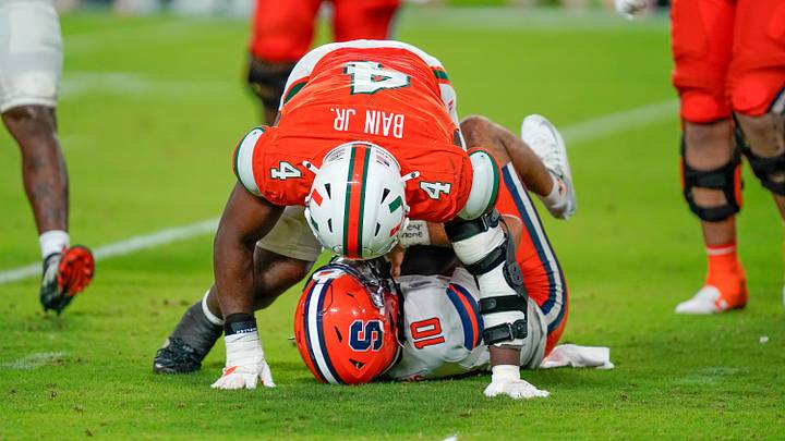 Nov 8, 2025; Miami Gardens, Florida, USA; Syracuse Orange quarterback Rickie Collins (10) is sacked by Miami Hurricanes defensive lineman Rueben Bain Jr. (4) during the fourth quarter at Hard Rock Stadium. Mandatory Credit: Jeff Romance-Imagn Images