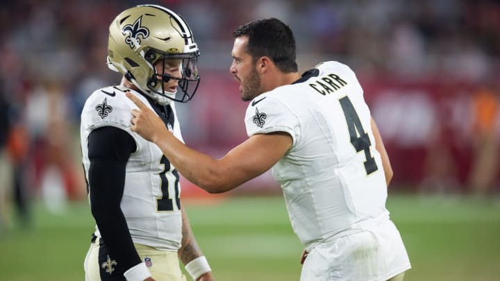 Aug 10, 2024; Glendale, Arizona, USA; New Orleans Saints quarterback Derek Carr (4) talks with Spencer Rattler (18) against the Arizona Cardinals during a preseason NFL game at State Farm Stadium. Mandatory Credit: Mark J. Rebilas-USA TODAY Sports