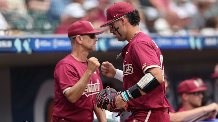 May 25, 2024; Charlotte, NC, USA; Florida State first baseman Daniel Cantu (32) fist bumps Florida State head coach Link Jarrett at the bottom of the first inning against Wake Forest during the ACC Baseball Tournament at Truist Field. Mandatory Credit: Cory Knowlton-Imagn Images