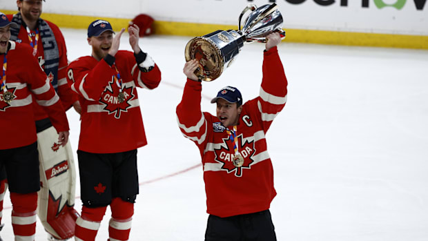 Hockey player in red uniform lifts troph