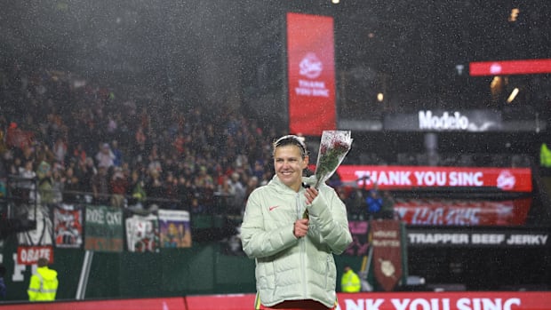 Soccer player Christine Sinclair stands on the pitch in Portland with a rose and looks out at the fans.