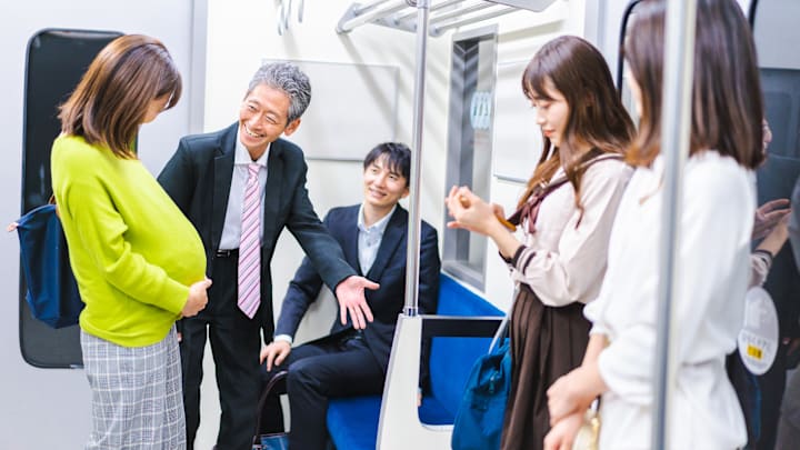 A man gives up his priority seat to a pregnant woman
