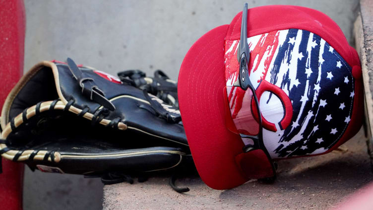 Cincinnati Reds glove and hat rest on the dugout steps.