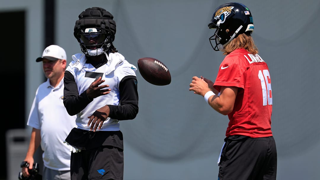 Jacksonville Jaguars wide receiver Brian Thomas Jr. (7), left, tosses the ball to quarterback Trevor Lawrence (16)