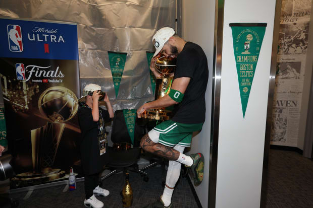 Celtics star Jayson Tatum celebrates with the Larry O'Brien Trophy in the locker room after winning his first NBA title.
