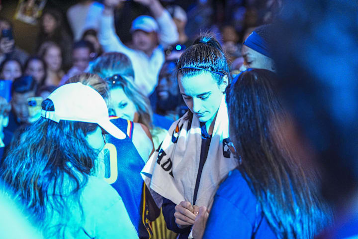 Indiana Fever guard Caitlin Clark signs autographs on her way off the court after the Fever defeated the Atlanta Dream.