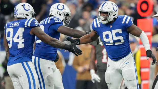 Colts defensive tackle Adetomiwa Adebawore (blue jersey with white helmet/pants) celebrates with his teammates after a play. 