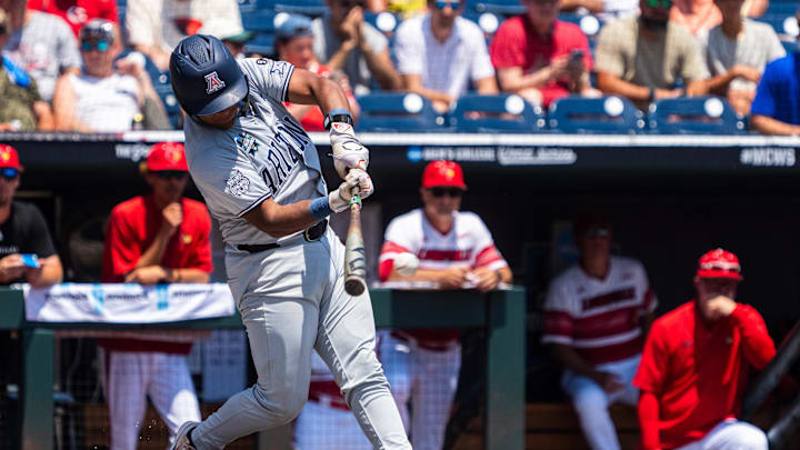 Jun 15, 2025; Omaha, Neb, USA; Arizona Wildcats catcher Adonys Guzman (18) hits a RBI single against the Louisville Cardinals during the first inning at Charles Schwab Field. Mandatory Credit: Dylan Widger-Imagn Images