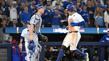 Oct 25, 2025; Toronto, Ontario, CAN; Toronto Blue Jays designated hitter George Springer (4) scores a run as Los Angeles Dodgers catcher Will Smith (16) looks on in the third inning during game two of the 2025 MLB World Series at Rogers Centre. Mandatory Credit: Dan Hamilton-Imagn Images