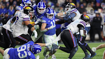 Nov 16, 2024; Provo, Utah, USA; Brigham Young Cougars defensive end Blake Mangelson (93) grabs the shirt of  Kansas Jayhawks running back Devin Neal (4) during the fourth quarter at LaVell Edwards Stadium. Mandatory Credit: Rob Gray-Imagn Images