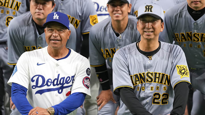 Mar 16, 2025; Bunkyo, Tokyo, Japan; Los Angeles Dodgers manager Dave Roberts (center left) and Hanshin Tigers manager Kyuji Fujikawa (22) pose for a photo with their teams after the game at Tokyo Dome. Mandatory Credit: Darren Yamashita-Imagn Images