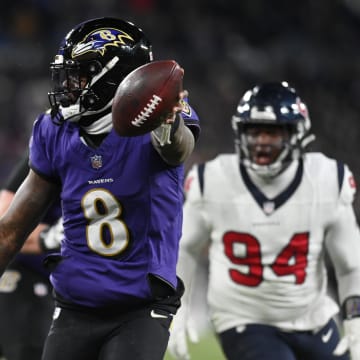 Jan 20, 2024; Baltimore, MD, USA; Baltimore Ravens quarterback Lamar Jackson (8) runs the ball to score a touchdown against Houston Texans defensive tackle Sheldon Rankins (98) and defensive tackle Khalil Davis (94) during the fourth quarter of a 2024 AFC divisional round game at M&T Bank Stadium. Mandatory Credit: Tommy Gilligan-USA TODAY Sports