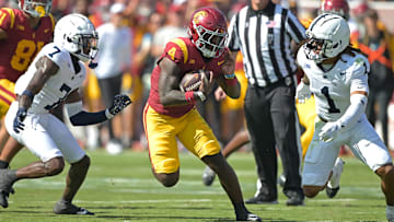 Oct 12, 2024; Los Angeles, California, USA; USC Trojans running back Woody Marks (4) runs the ball for a first down before he is stopped by Penn State Nittany Lions safety Jaylen Reed (1) and cornerback Zion Tracy (7) in the first half at United Airlines Field at the Los Angeles Memorial Coliseum. Mandatory Credit: Jayne Kamin-Oncea-Imagn Images