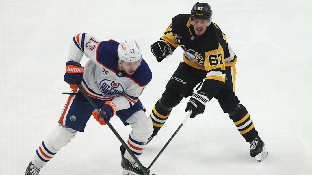 Dec 16, 2025; Pittsburgh, Pennsylvania, USA;  Edmonton Oilers center Mattias Janmark (13) moves the puck against Pittsburgh Penguins right wing Rickard Rakell (67) during the third period at PPG Paints Arena. Mandatory Credit: Charles LeClaire-Imagn Images