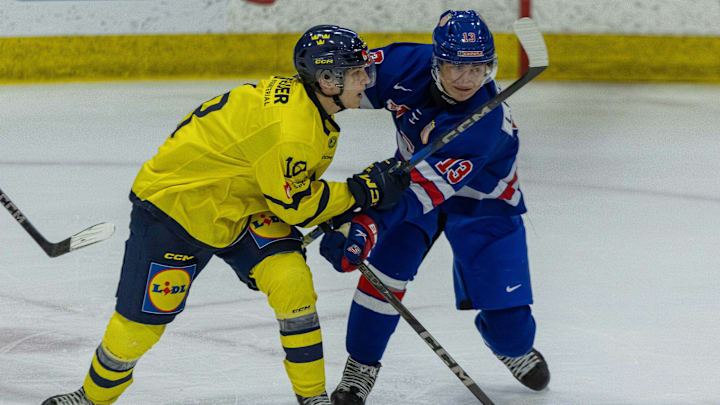 Aug 2, 2024; Plymouth, MI, USA; USA’s defenceman Lukas Fischer (13) battles for position with Sweden's forward Victor Eklund (18) during the first period of the 2024 World Junior Summer Showcase at USA Hockey Arena. Mandatory Credit: David Reginek-Imagn Images