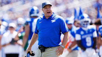 Aug 30, 2025; Lexington, Kentucky, USA; Kentucky Wildcats head coach Mark Stoops discusses a play with a referee during the first quarter against the Toledo Rockets at Kroger Field. Mandatory Credit: Jordan Prather-Imagn Images