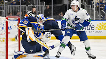 Jan 27, 2025; St. Louis, Missouri, USA;  St. Louis Blues goaltender Joel Hofer (30) defends the net against Vancouver Canucks center Linus Karlsson (94) during the third period at Enterprise Center. Mandatory Credit: Jeff Curry-Imagn Images