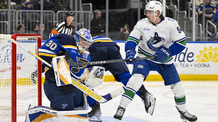 Jan 27, 2025; St. Louis, Missouri, USA;  St. Louis Blues goaltender Joel Hofer (30) defends the net against Vancouver Canucks center Linus Karlsson (94) during the third period at Enterprise Center. Mandatory Credit: Jeff Curry-Imagn Images