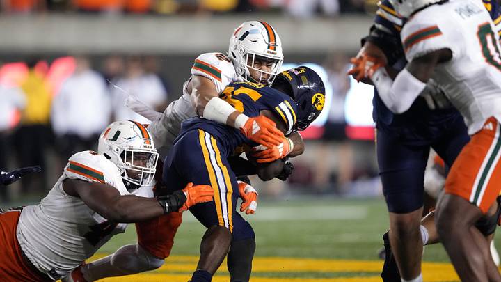 Oct 5, 2024; Berkeley, California, USA; Miami Hurricanes linebacker Raul Aguirre Jr. (center left) and defensive lineman Rueben Bain Jr. (left) tackle California Golden Bears running back Jaivian Thomas (center right) during the fourth quarter at California Memorial Stadium. Mandatory Credit: Darren Yamashita-Imagn Images