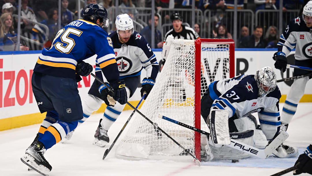 May 2, 2025; St. Louis, Missouri, USA; Winnipeg Jets defenseman Luke Schenn (5) and goaltender Connor Hellebuyck (37) defend the net against St. Louis Blues right wing Jordan Kyrou (25) in game six of the first round of the 2025 Stanley Cup Playoffs at Enterprise Center. Mandatory Credit: Connor Hamilton-Imagn Images