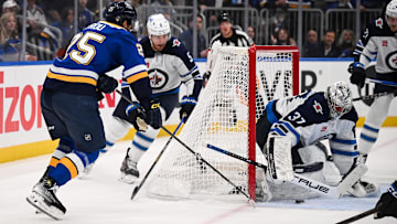 May 2, 2025; St. Louis, Missouri, USA; Winnipeg Jets defenseman Luke Schenn (5) and goaltender Connor Hellebuyck (37) defend the net against St. Louis Blues right wing Jordan Kyrou (25) in game six of the first round of the 2025 Stanley Cup Playoffs at Enterprise Center. Mandatory Credit: Connor Hamilton-Imagn Images