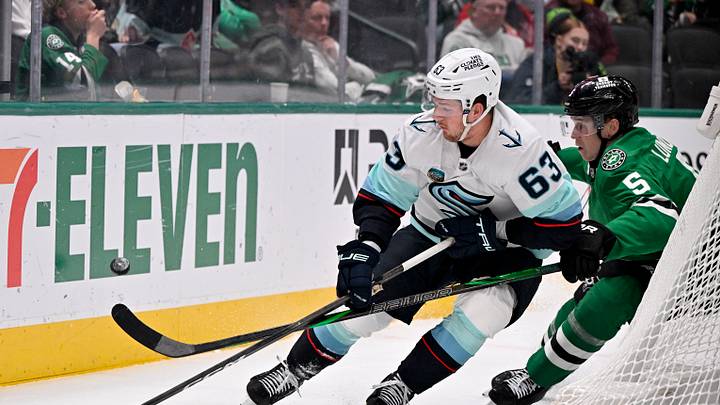 Feb 25, 2026; Dallas, Texas, USA;  Seattle Kraken right wing Jacob Melanson (63) and Dallas Stars defenseman Nils Lundkvist (5) battle for control of the puck during the first period at the American Airlines Center. Mandatory Credit: Jerome Miron-Imagn Images