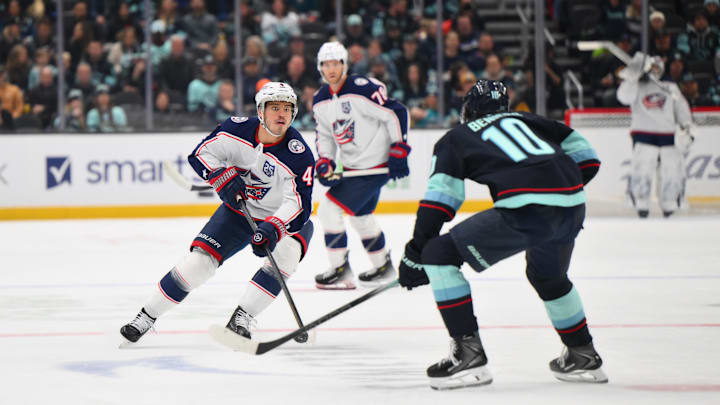 Nov 11, 2025; Seattle, Washington, USA; Columbus Blue Jackets center Cole Sillinger (4) plays the puck while defended by Seattle Kraken center Matty Beniers (10) during the first period at Climate Pledge Arena. Mandatory Credit: Steven Bisig-Imagn Images