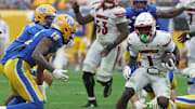 Sep 27, 2025; Pittsburgh, Pennsylvania, USA;  Louisville Cardinals running back Isaac Brown (1) runs the ball against Pittsburgh Panthers defensive back Rashad Battle (15) during the fourth quarter at Acrisure Stadium. Mandatory Credit: Charles LeClaire-Imagn Images