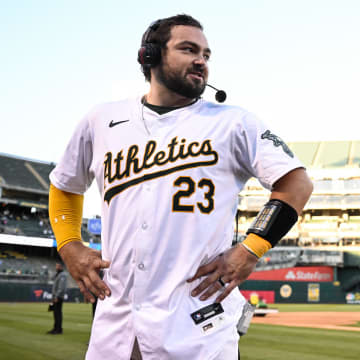 Sep 2, 2024; Oakland, California, USA; Oakland Athletics catcher Shea Langeliers (23) does a postgame interview after his walk-off home run against the Seattle Mariners as outfielder Lawrence Butler (4) and shortstop Max Schuemann (12) prepare to douse him at Oakland-Alameda County Coliseum.