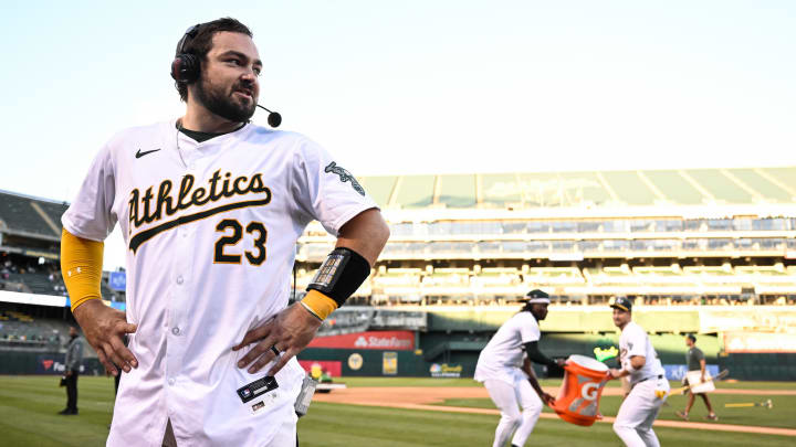 Sep 2, 2024; Oakland, California, USA; Oakland Athletics catcher Shea Langeliers (23) does a postgame interview after his walk-off home run against the Seattle Mariners as outfielder Lawrence Butler (4) and shortstop Max Schuemann (12) prepare to douse him at Oakland-Alameda County Coliseum.