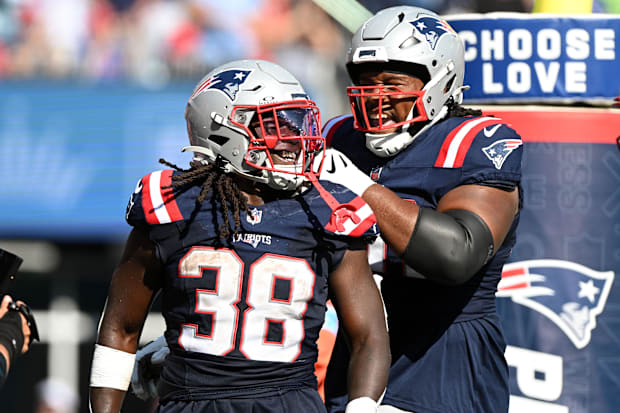 New England Patriots running back Rhamondre Stevenson (38) celebrates with offensive tackle Caedan Wallace (70).