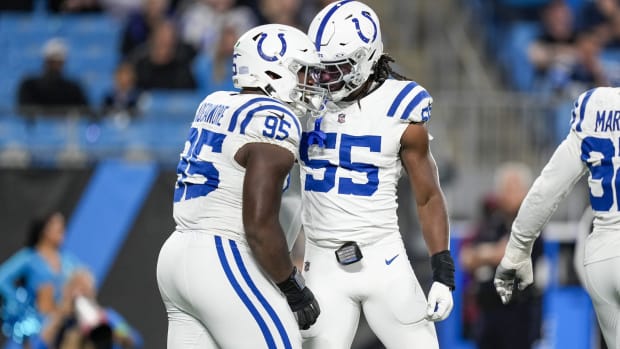 Colts defensive end Isaiah Land (all-white uniforms with blue trim) celebrates a big play with a teammate. 