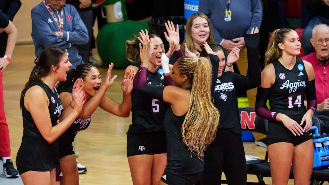 Dec 14, 2025; Lincoln, NE, USA; Texas A&M Aggies middle blocker Morgan Perkins (21) celebrates with outside hitter Lexi Guinn (5) and opposite Taryn Morris (6) after a point against the Nebraska Cornhuskers during the second set at Bob Devaney Sports Center. Mandatory Credit: Dylan Widger-Imagn Images
