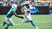 Oct 5, 2025; Charlotte, North Carolina, USA; Carolina Panthers running back Rico Dowdle (5) with the ball as Miami Dolphins linebacker Tyrel Dodson (25) defends in the second quarter at Bank of America Stadium. Mandatory Credit: Bob Donnan-Imagn Images