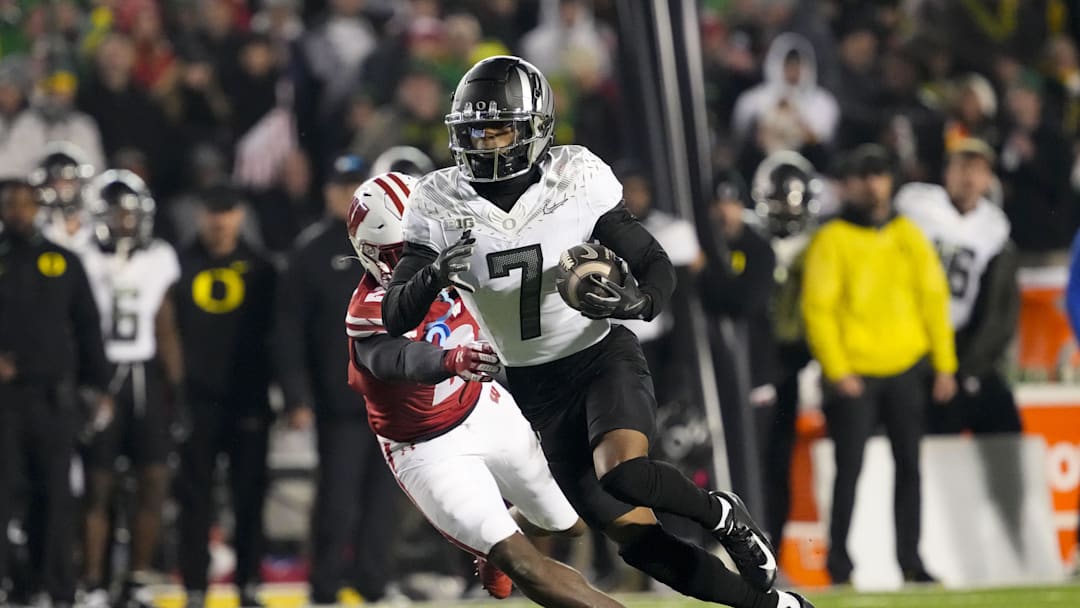 Nov 16, 2024; Madison, Wisconsin, USA;  Oregon Ducks wide receiver Evan Stewart (7) rushes with the football in front of Wisconsin Badgers cornerback Ricardo Hallman (2) after catching a pass during the fourth quarter at Camp Randall Stadium. Mandatory Credit: Jeff Hanisch-Imagn Images
