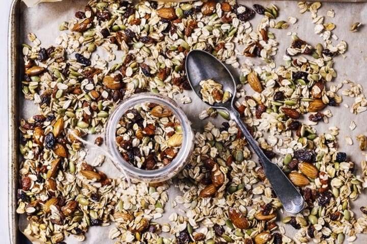 A tray of granola with a spoon and jar