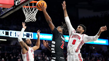 Cincinnati Bearcats guard Jizzle James (2) rises to the basket as Houston Cougars guard Mylik Wilson (8) defends in the second half of an NCAA college basketball game between the Houston Cougars and the Cincinnati Bearcats, Saturday, Feb. 10, 2024, at Fifth Third Arena in Cincinnati.