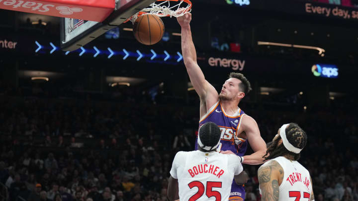 Mar 7, 2024; Phoenix, Arizona, USA; Phoenix Suns forward Drew Eubanks (14) dunks over Toronto Raptors forward Chris Boucher (25) and Toronto Raptors guard Gary Trent Jr. (33) during the second half at Footprint Center. Mandatory Credit: Joe Camporeale-USA TODAY Sports