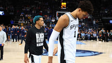 Feb 3, 2025; Memphis, Tennessee, USA; San Antonio Spurs forward Jeremy Sochan (10) and San Antonio Spurs center Victor Wembanyama (1) walk off the court after a delayed start to the game, as medical personnel check on a fan before the game against the Memphis Grizzlies at FedExForum. Mandatory Credit: Petre Thomas-Imagn Images